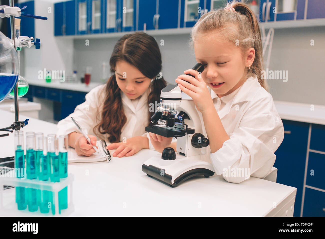 Due bambini piccoli in camice da laboratorio di chimica di apprendimento in  laboratorio scolastico. Studiando gli ingredienti per gli esperimenti . Per  i giovani scienziati occhiali protettivi mak Foto stock - Alamy