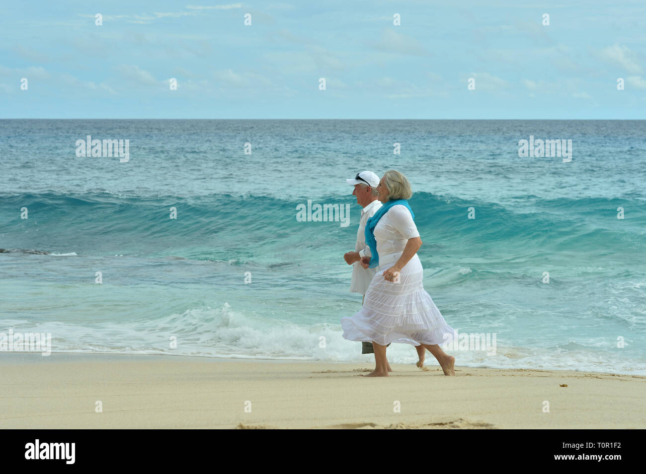 Ritratto di felice coppia di anziani in esecuzione sulla spiaggia tropicale Foto Stock