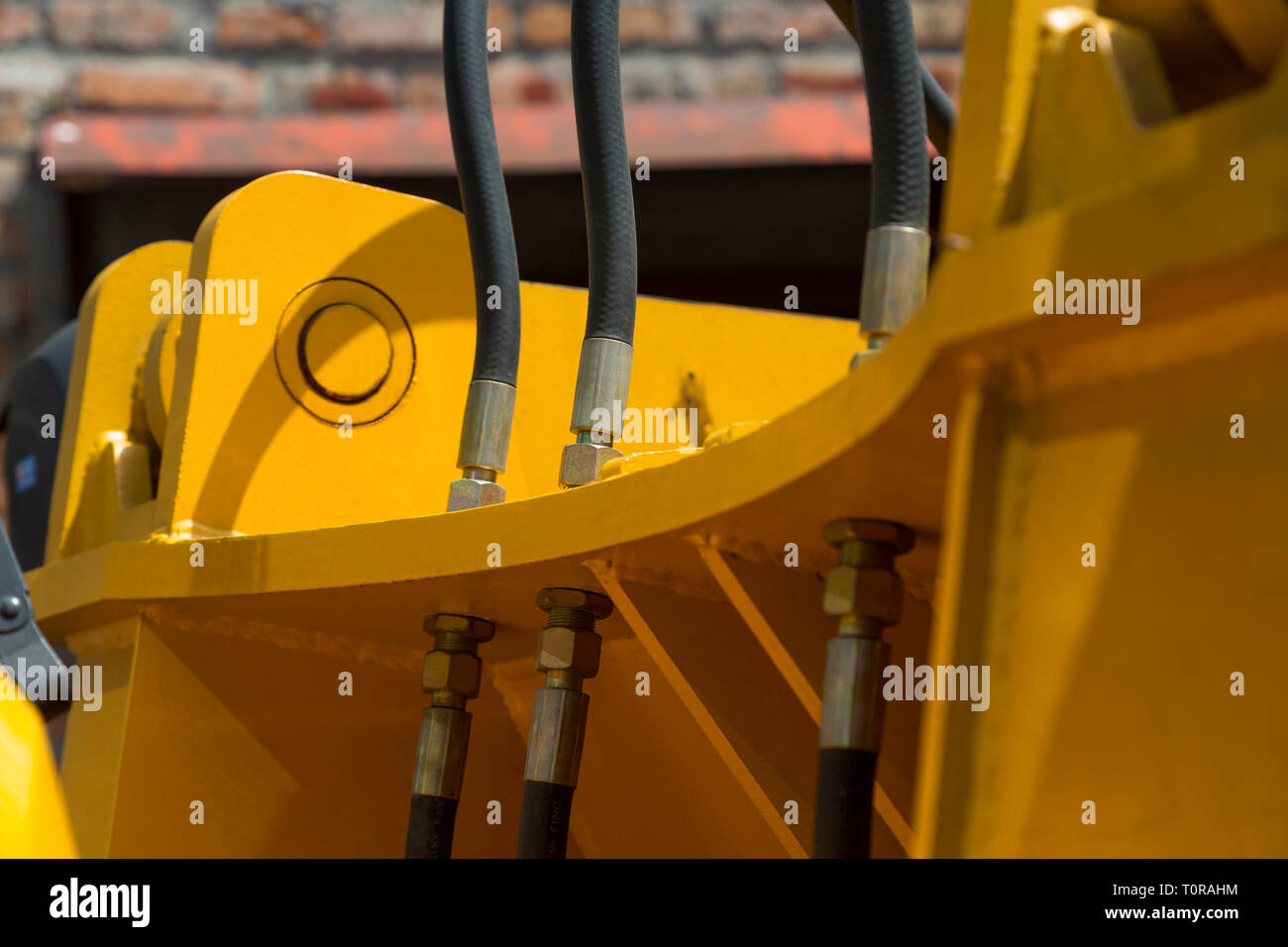 I tubi idraulici flessibili connessioni e altri meccanismi di giallo macchine stradali close-up su uno sfondo sfocato del vecchio muro di mattoni Foto Stock