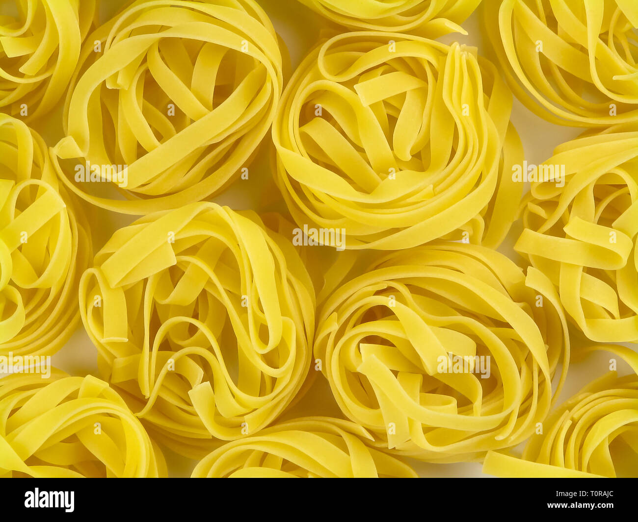 Giallo crudo pasta italiana tagliatelle nidi texture top view close-up Foto Stock