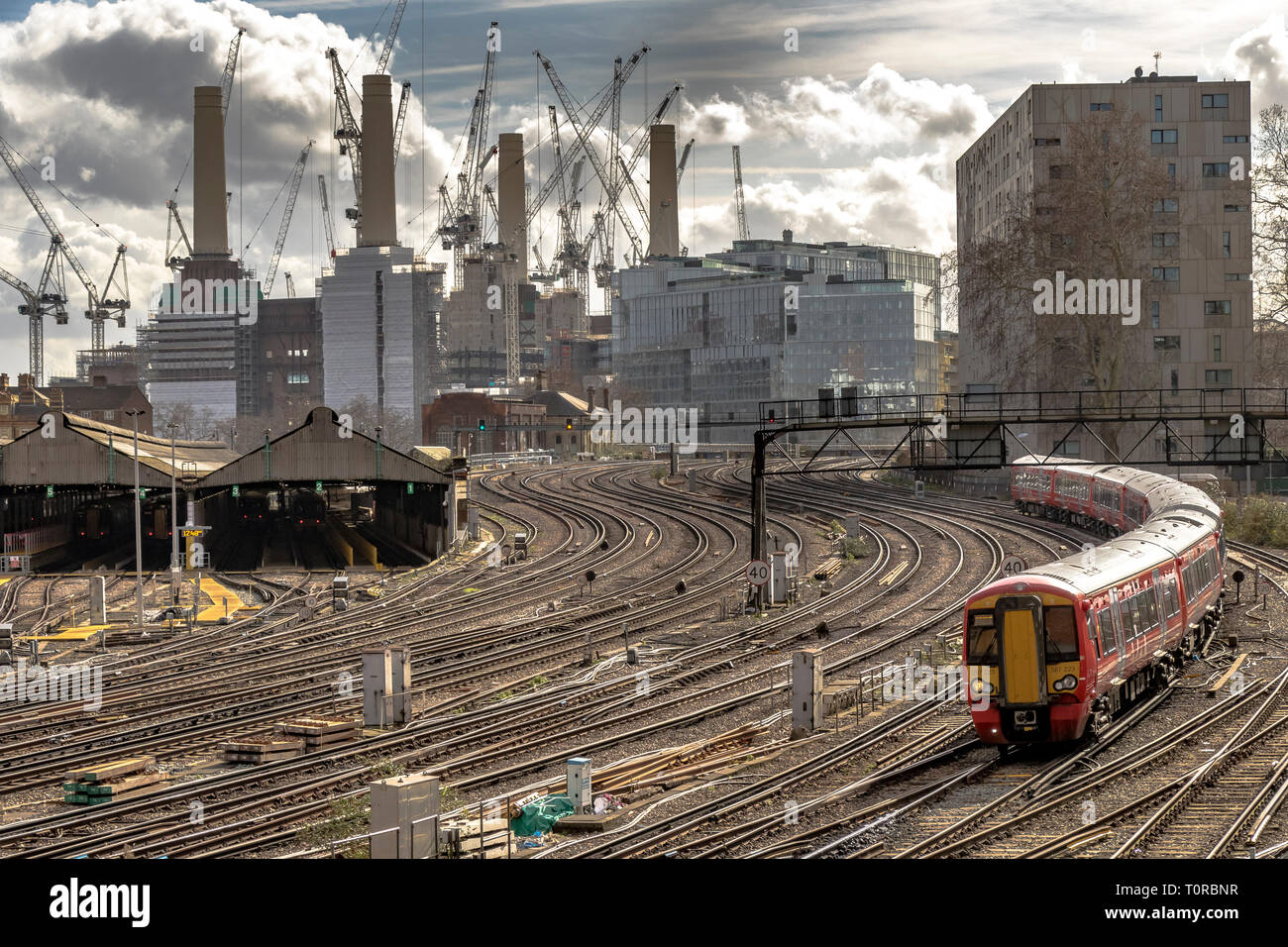 Il Gatwick Express si avvicina a Ebury Bridge per l'avvicinamento finale alla Victoria Station, con la Battersea Power Station in lontananza, Londra, Regno Unito Foto Stock