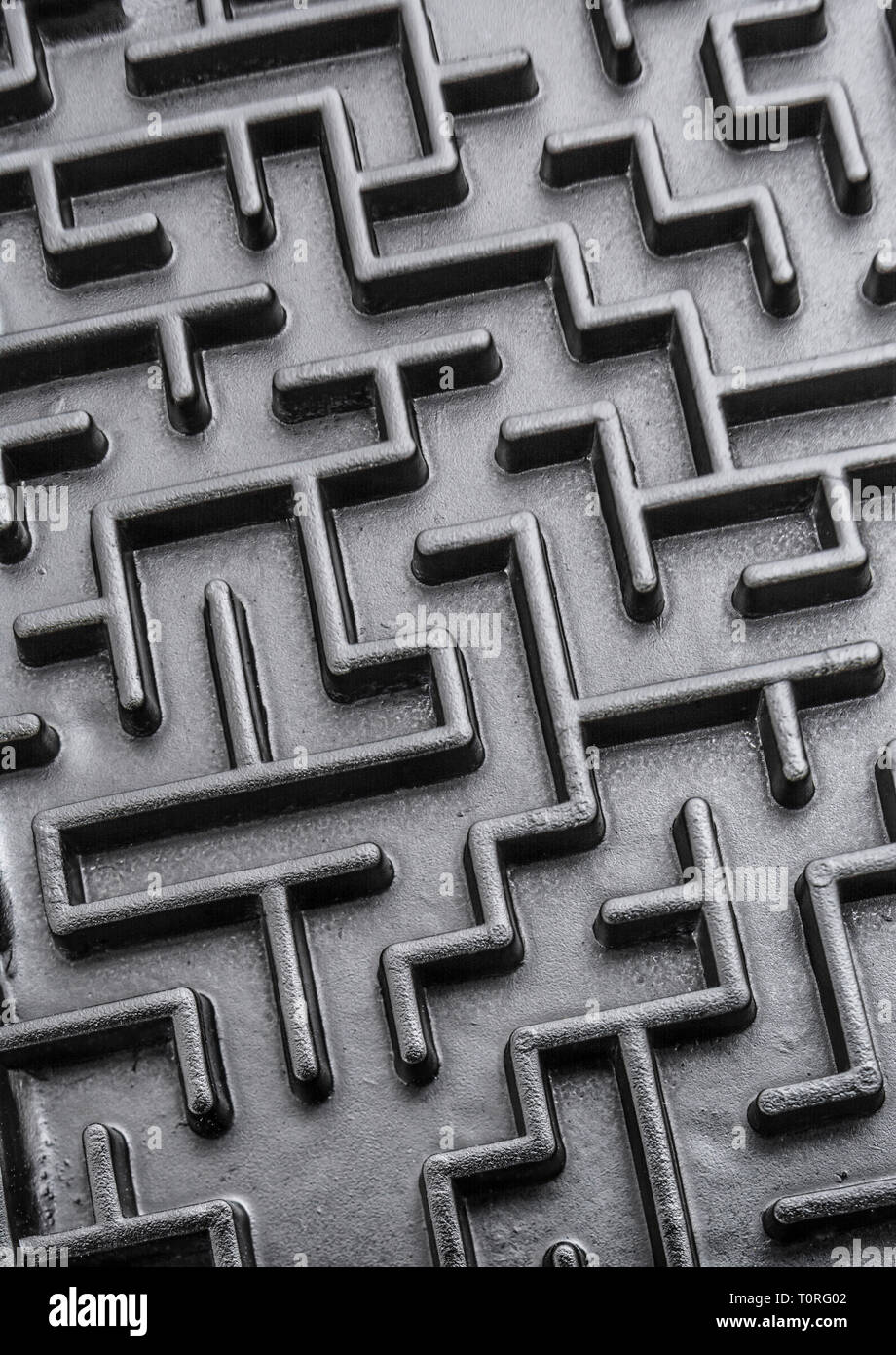 Macro shot di piccolo labirinto giocattolo dipinto di nero. Per complessi, sempre perduti, navigare, risolvere problemi, obiettivi irraggiungibili, negoziati Brexit. Foto Stock