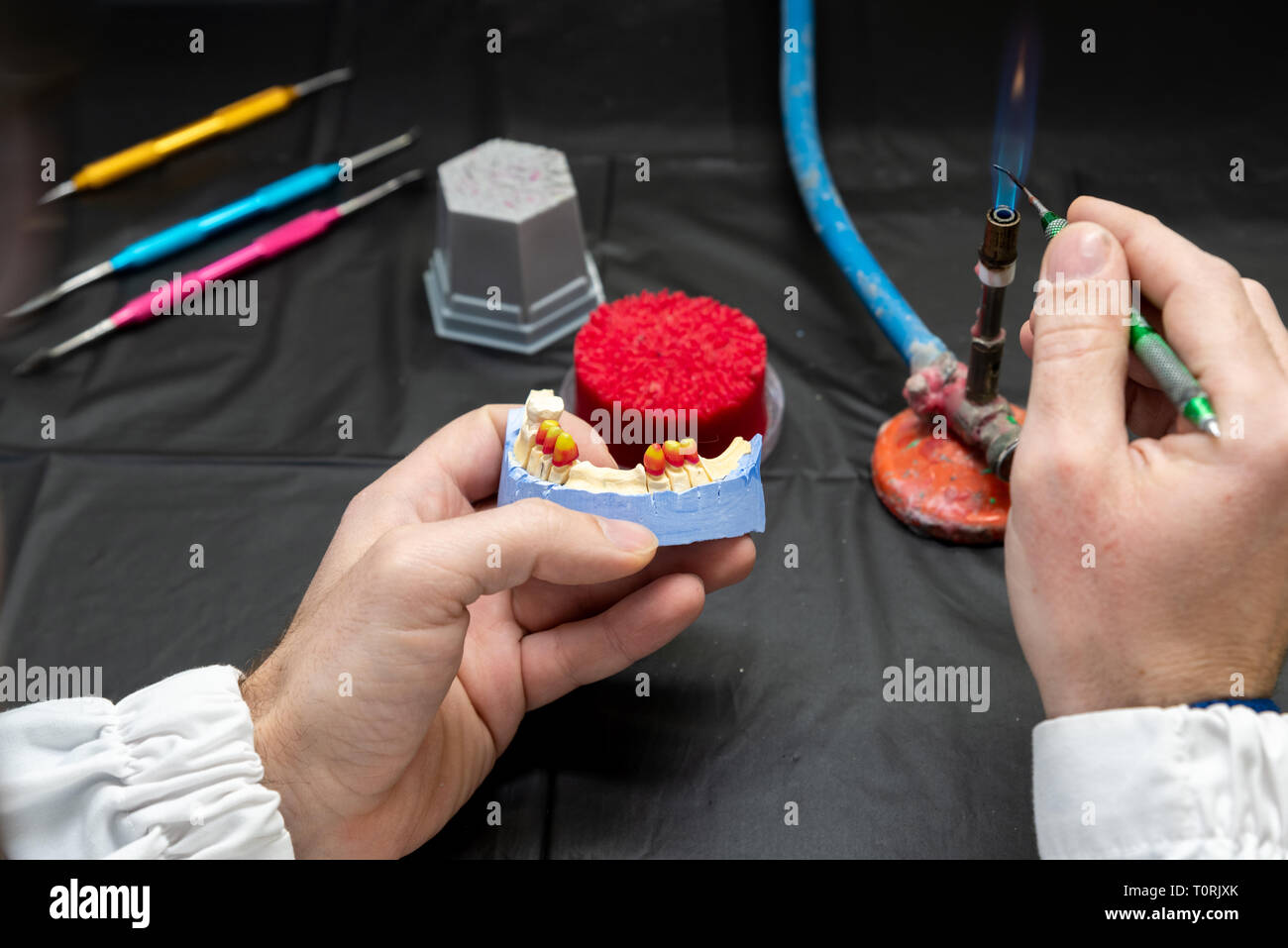 Odontotecnico o dentista uomo che lavora con le dentiere in un laboratorio con la cera su un modello di ganascia Foto Stock