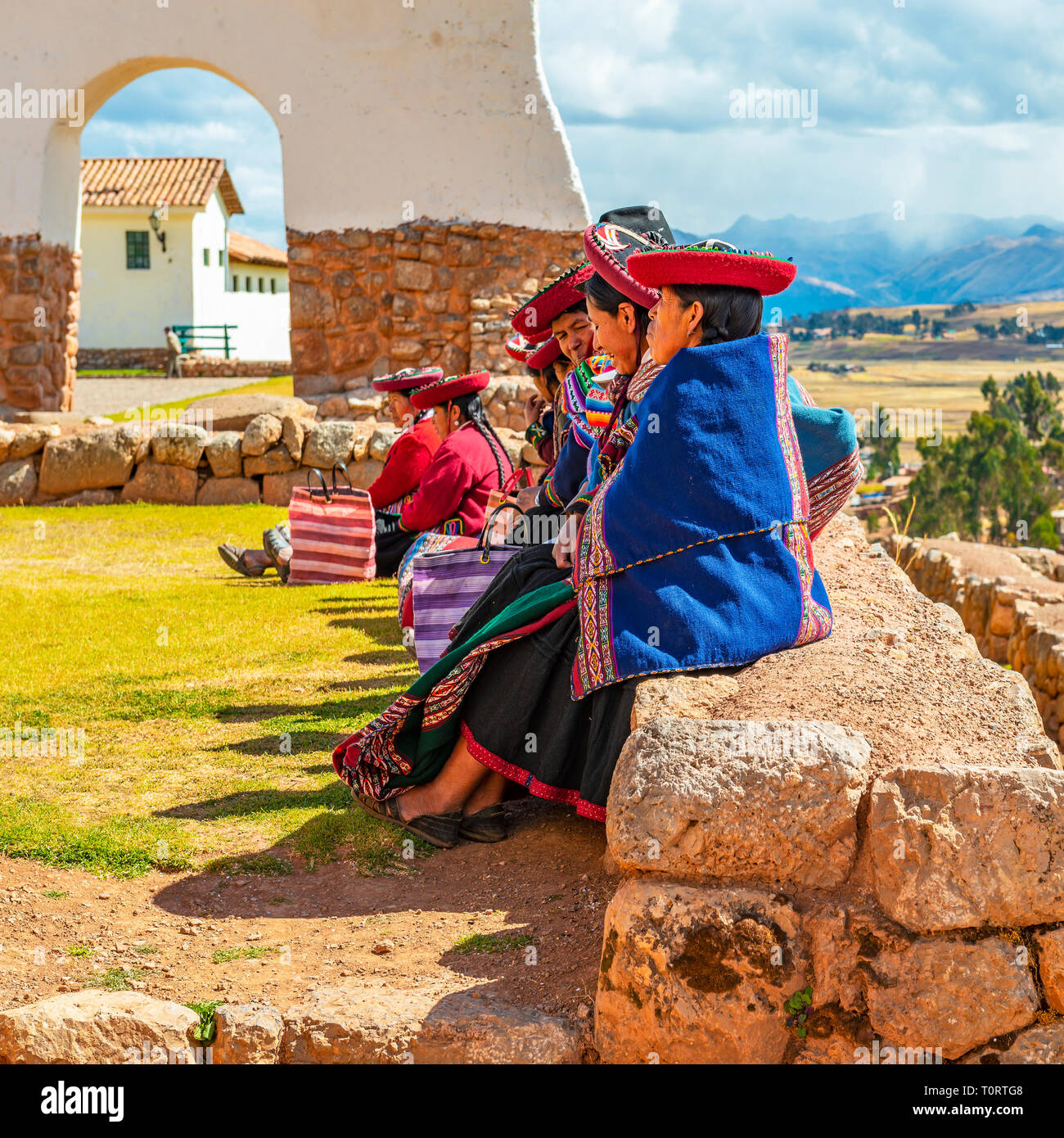 Un gruppo di peruviani indigeni Quechua donna seduta su un antico muro Inca in archeologici Inca rovina di Chinchero, Provincia di Cusco, Perù. Foto Stock