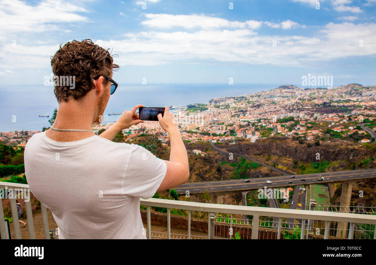 Giovane uomo turistica prendendo una foto della città di Funchal sull' isola di Madeira Portogallo, sul giorno d'estate. Foto Stock