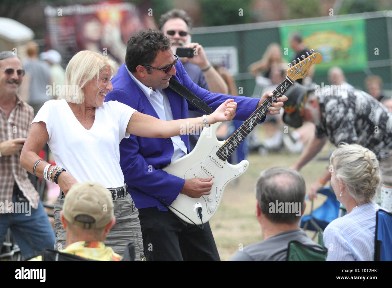 Un concerto ventola è mostrato air guitaring lungo con il chitarrista Jeff Pitchell durante un concerto all'aperto le prestazioni. Foto Stock