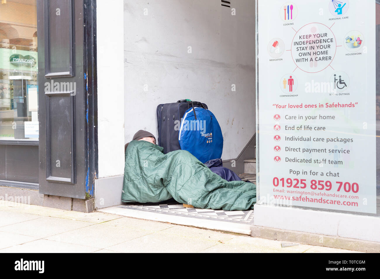Senzatetto uomo dorme in modo irregolare a un negozio che porta in centro citta' di Warrington, Cheshire, Regno Unito Foto Stock