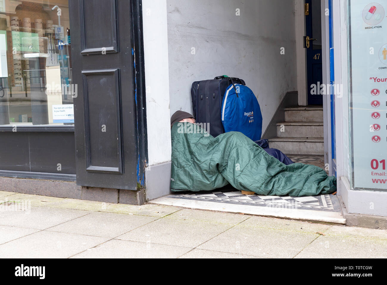 Senzatetto uomo dorme in modo irregolare a un negozio che porta in centro citta' di Warrington, Cheshire, Regno Unito Foto Stock