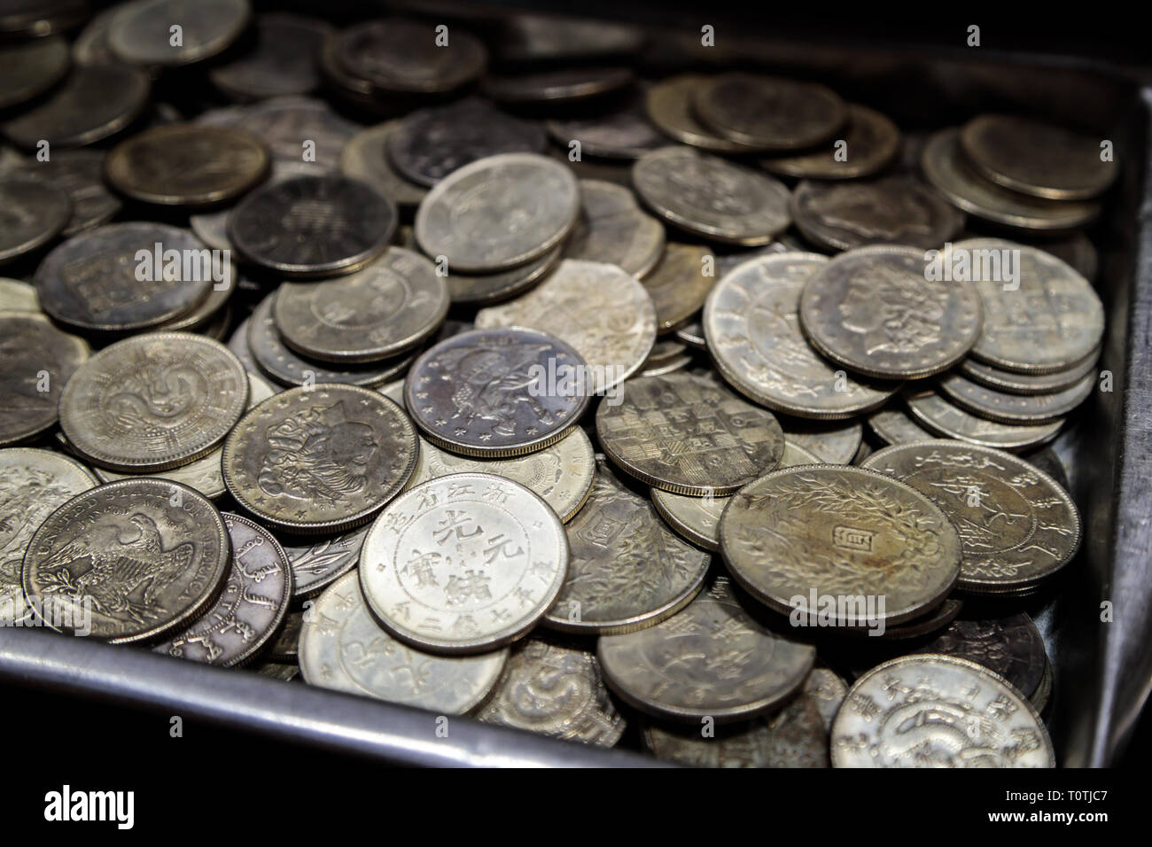 Pila di monete metalliche di diverse confessioni e diversi paesi nella scatola di metallo Foto Stock