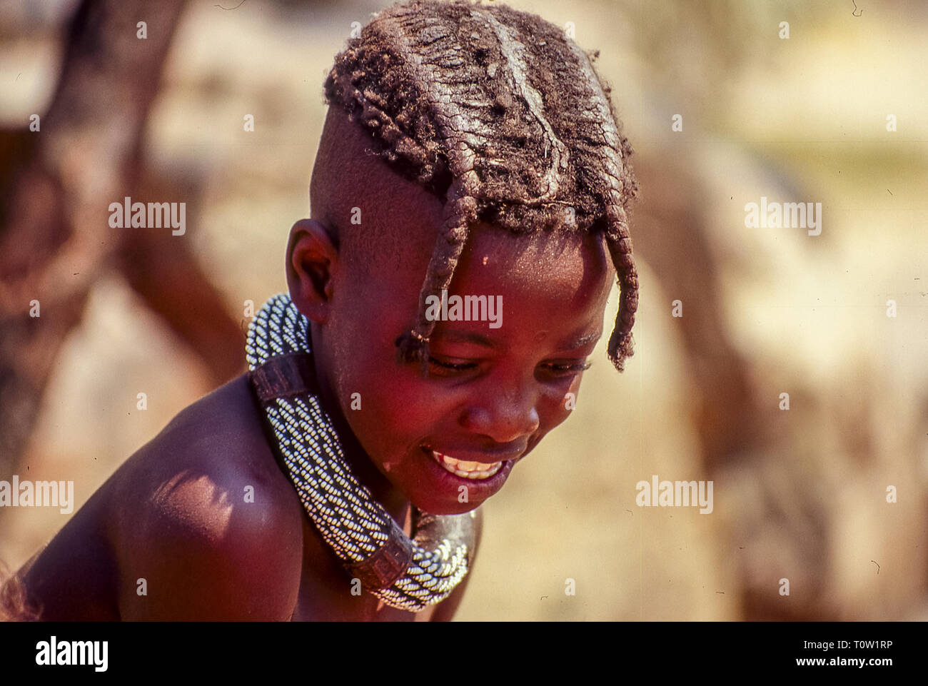 Un bambino himba sport una bella acconciatura con trecce e un ampio collare in metallo a Epupa Falls in Namibia Foto Stock