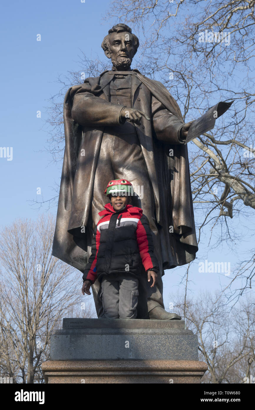 African American bambino si appoggia contro la statua di Abramo Lincoln in Prospect Park di Brooklyn, New York. Foto Stock