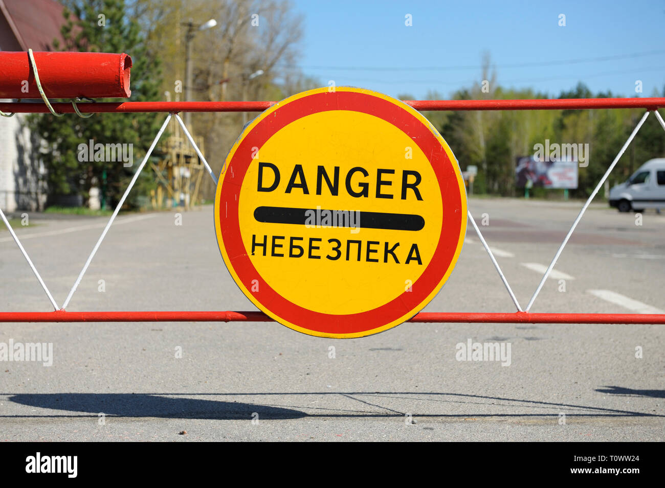 Segno di pericolo e a veicolo in marcia dalla barriera sul punto di attraversamento Dytiatky in cui Chernobyl Zona di esclusione inizia.Il 20 aprile 2018. Dytiatky, Ucraina Foto Stock