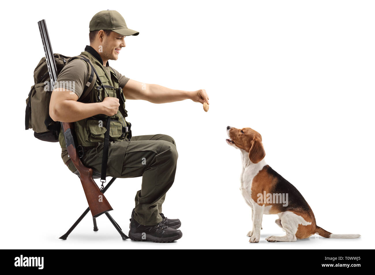Il cacciatore di sesso maschile seduto su una sedia e dando un biscotto al suo beagle cane da caccia isolati su sfondo bianco Foto Stock