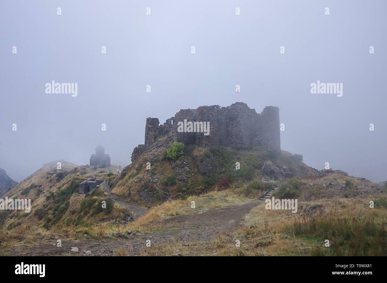 Fortezza di Amberd e San Astvatsatsin (Santa Madre di Dio) Chiesa in pendenza della montagna Aragats tra le nuvole. Armenia Foto Stock
