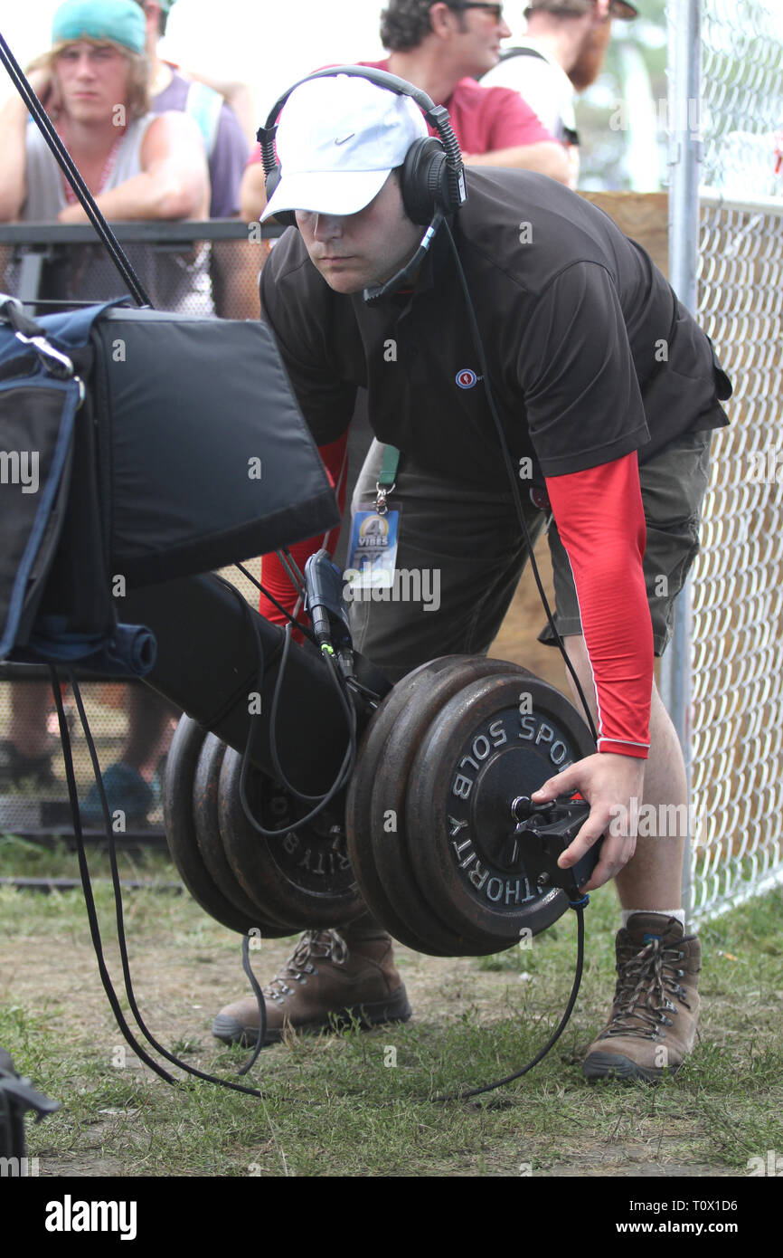 Un lavoratore di produzione viene illustrato il controllo di un braccio di grandi dimensioni della fotocamera durante un outdoor i festival estivi di musica. Foto Stock