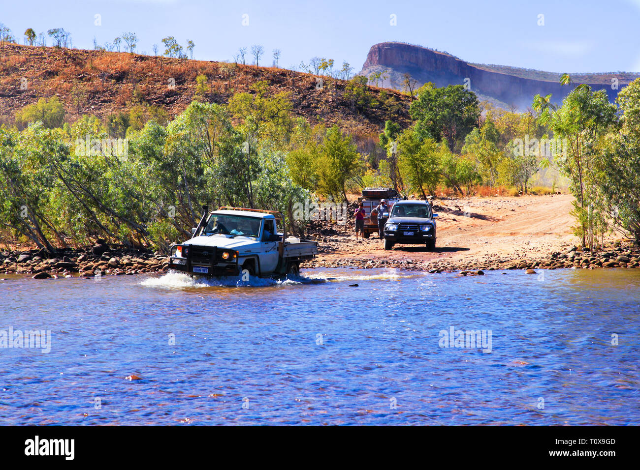 Kimberley, Australia - Luglio 2016: veicoli 4WD attraversare il fiume di Pentecoste sulla Gibb River Road, con la gamma di Cockburn in background. Foto Stock