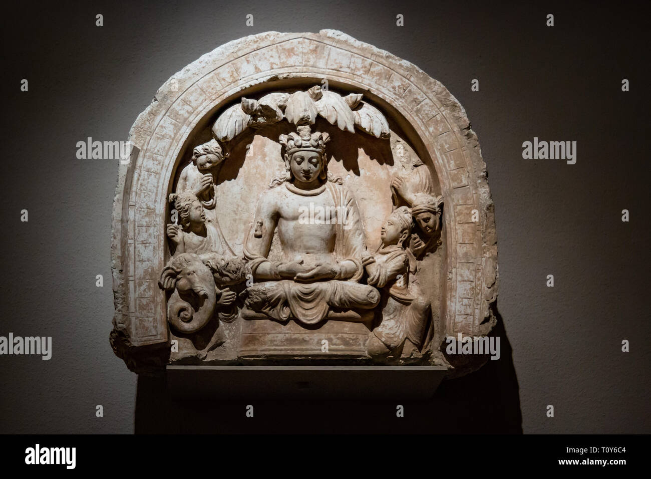 Nicchia con un Buddha seduto e gli operatori è una rara lunetta dal complesso buddista a Hadda, Afghanistan. Shakyamuni, il Buddha storico nato come principe Siddharta, è mostrato come un bodhisattva indossando la jeweled turbante e ornamenti di un royal. È in mostra al Metropolitan Museum of Art di New York City. Foto Stock