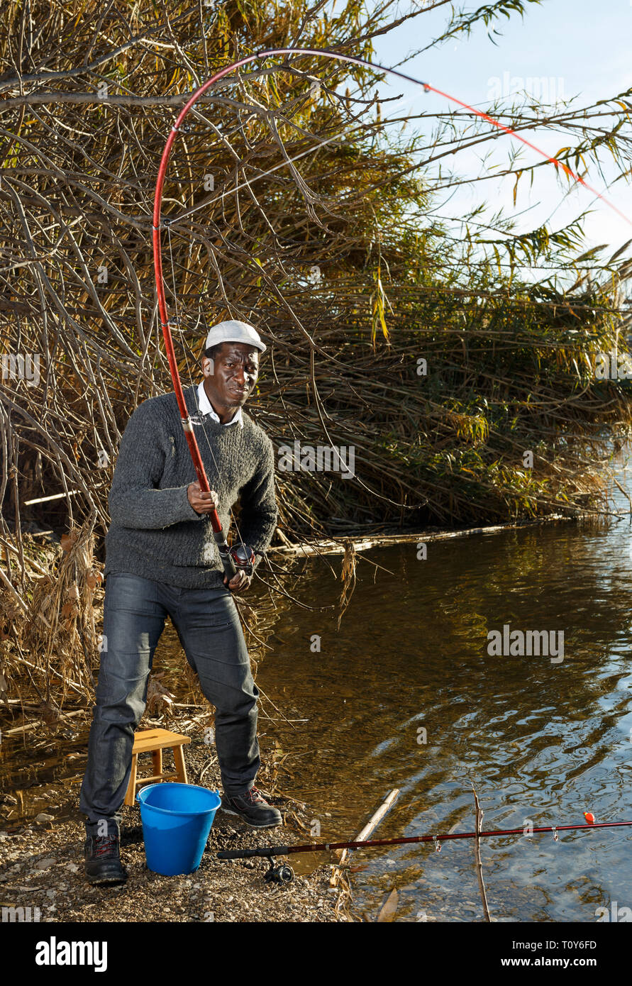 Emotional ritratto di uomo africano tirando con asta di pescare sul fiume Foto Stock