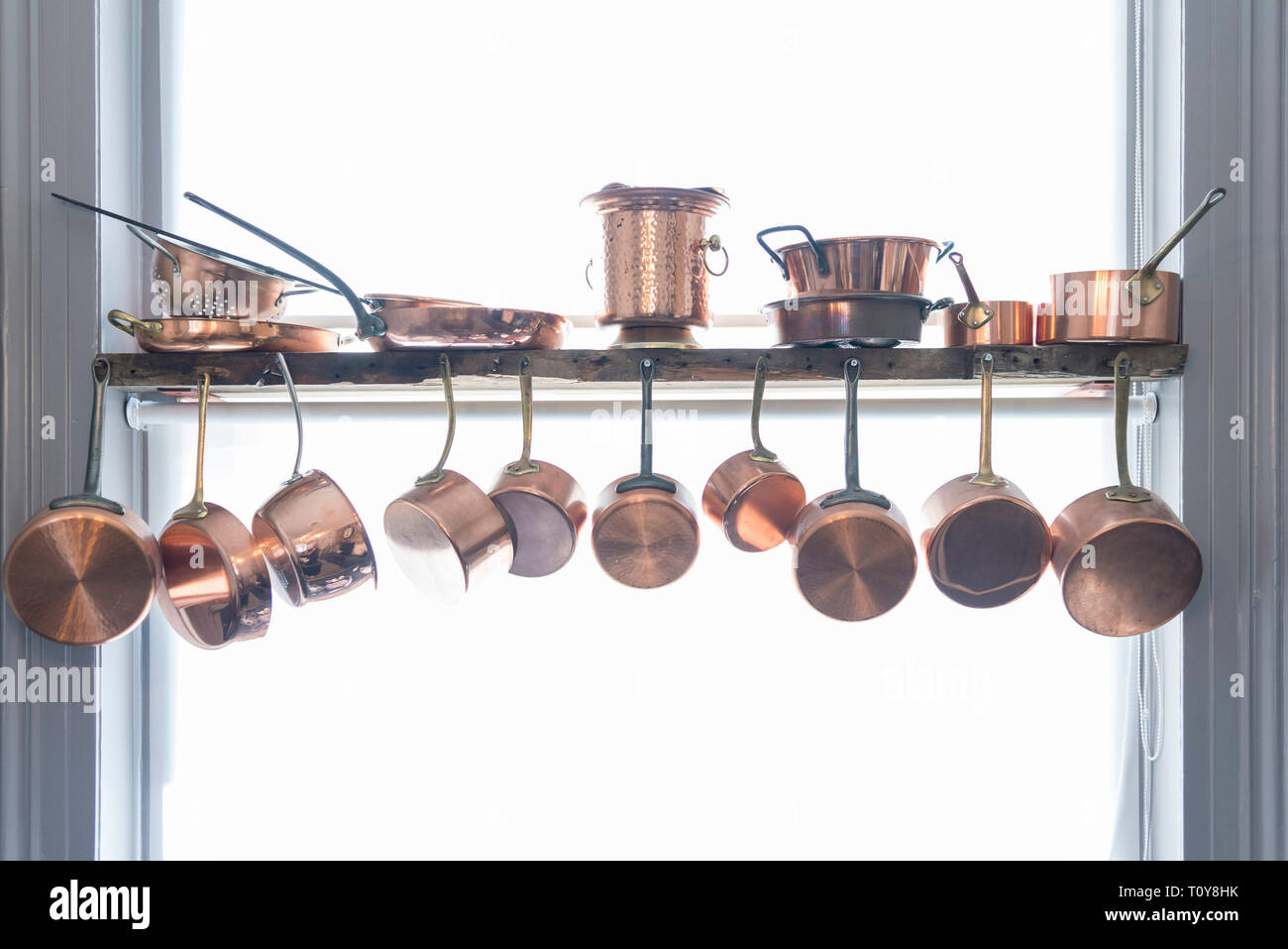 Una raccolta di post di rame e padelle pende verso il basso in una cucina. Foto Stock