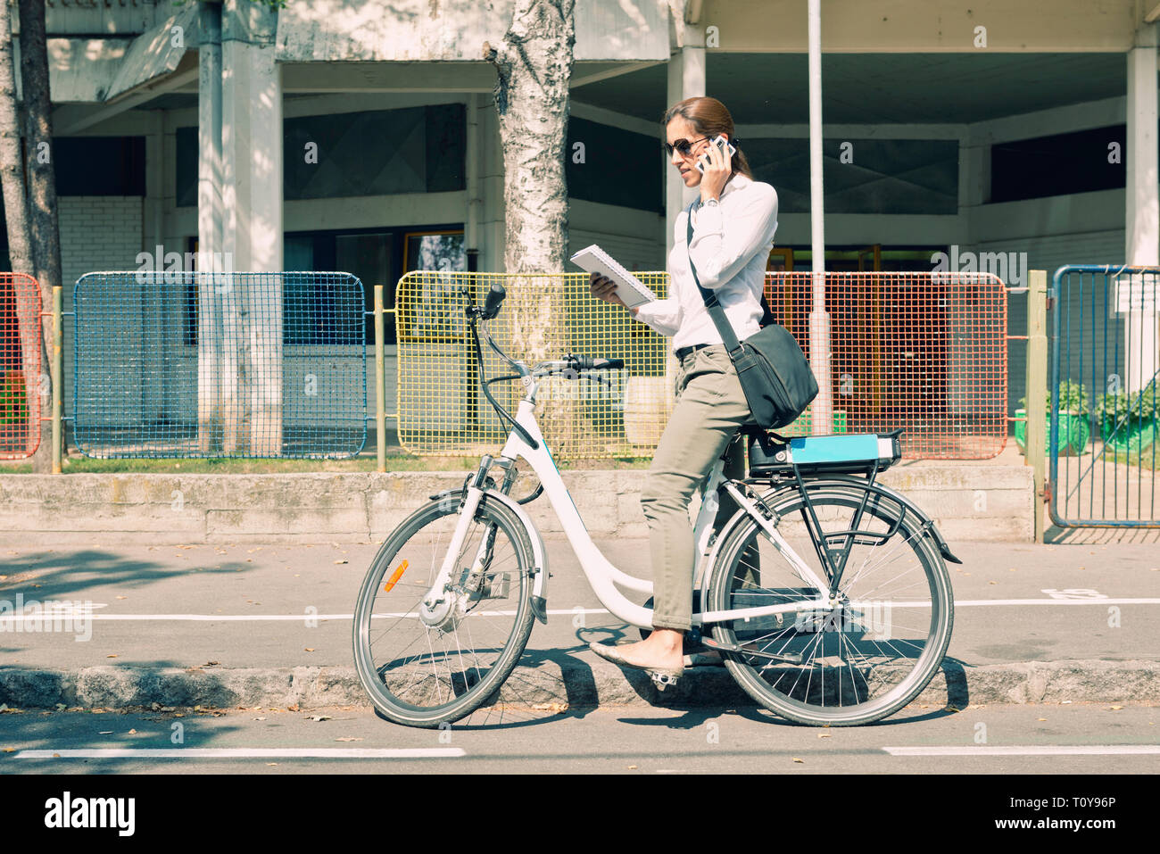 E-bike commuter si ferma sulla strada per prendere una chiamata Foto Stock