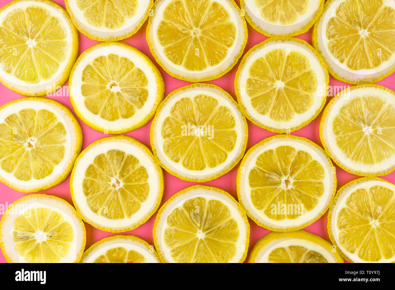 Modello realizzato da fettine di limone fresco su un sfondo rosa, vista aerea, flatlay. Sfondo di frutta. Foto Stock