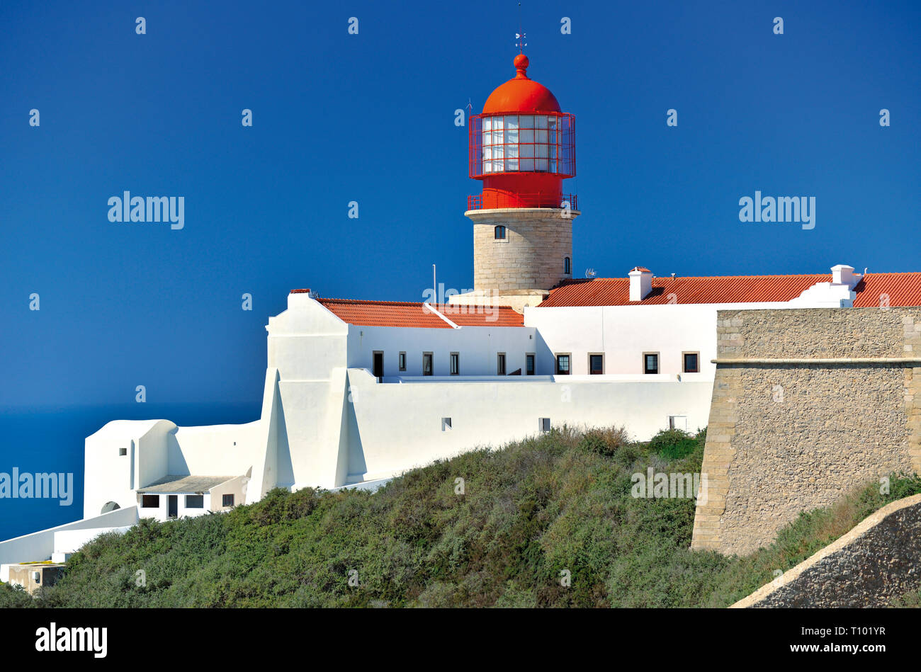 Edificio dipinto di bianco con faro rosso in contrasto con baby blue sky in una giornata di sole Foto Stock