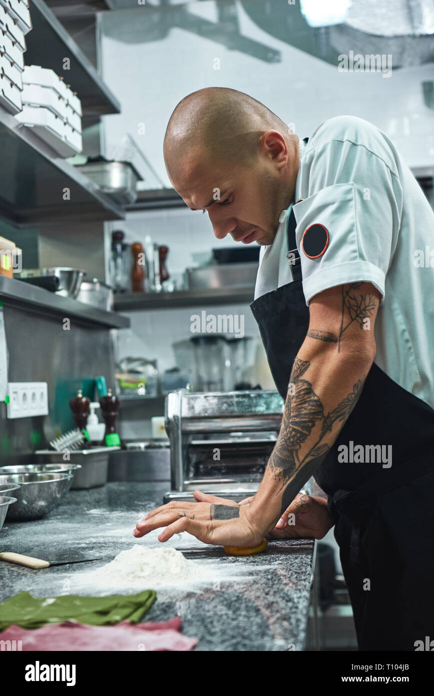 Il processo di lavorazione. Foto verticale di bello chef professionale con  tatuaggi sulle mani di impastare la pasta nel ristorante cucina. La pasta  italiana Foto stock - Alamy