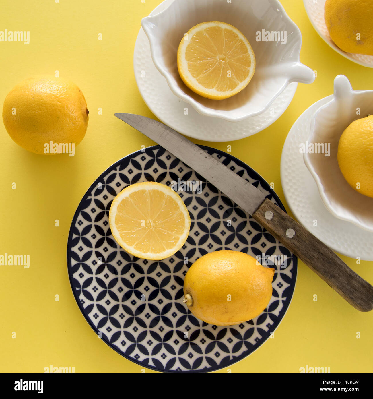 Crudo fresco di limoni e porcellane tablewares fresco su sfondo giallo. Still Life, sfondo, fresh food design Foto Stock