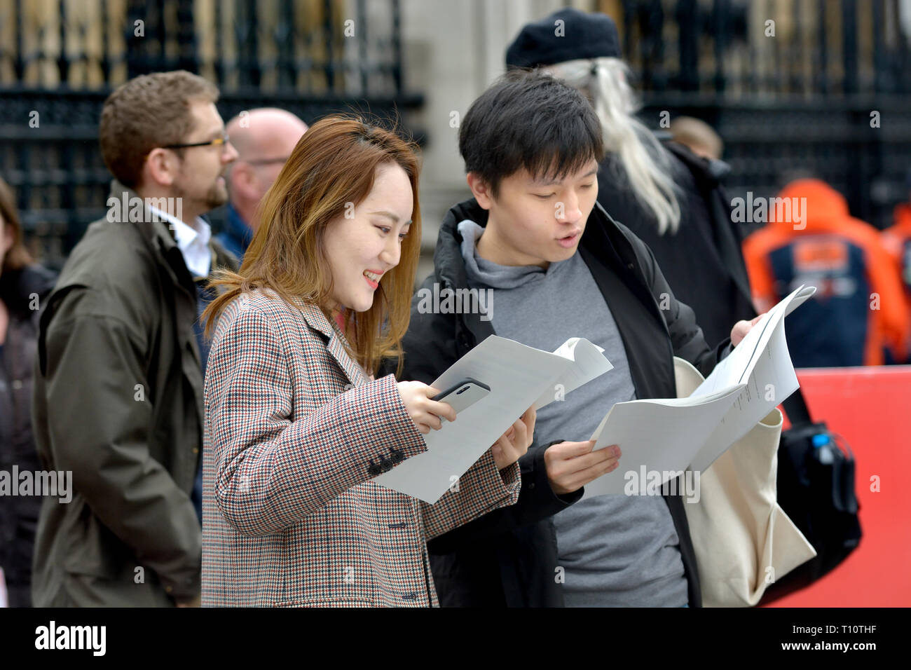 Londra, Inghilterra, Regno Unito. Coppia giapponese in piazza del Parlamento dopo aver visitato le case del Parlamento, guardando la letteratura circa la loro visita Foto Stock