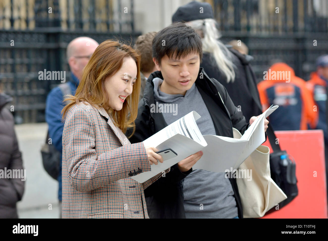 Londra, Inghilterra, Regno Unito. Coppia giapponese in piazza del Parlamento dopo aver visitato le case del Parlamento, guardando la letteratura circa la loro visita Foto Stock