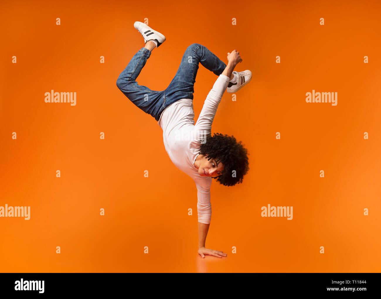 Uomo nero in equilibrio su una mano su Orange Foto Stock