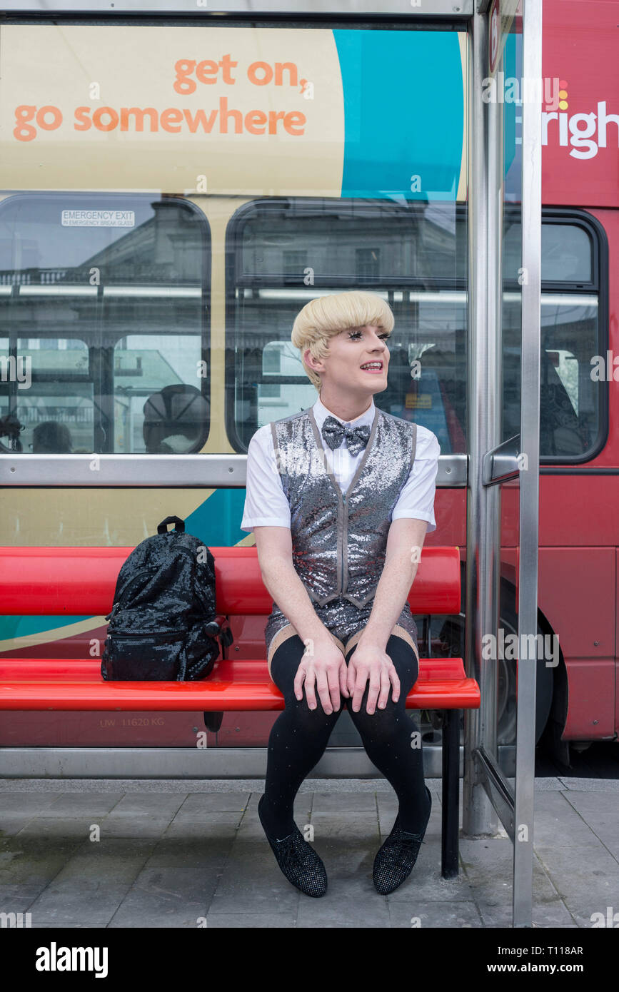 A Brighton trascinare artista attende ad una fermata di autobus. Foto Stock