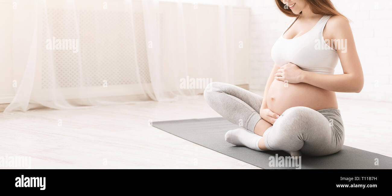Attiva donna incinta seduta sul pavimento dopo facendo sport Foto Stock