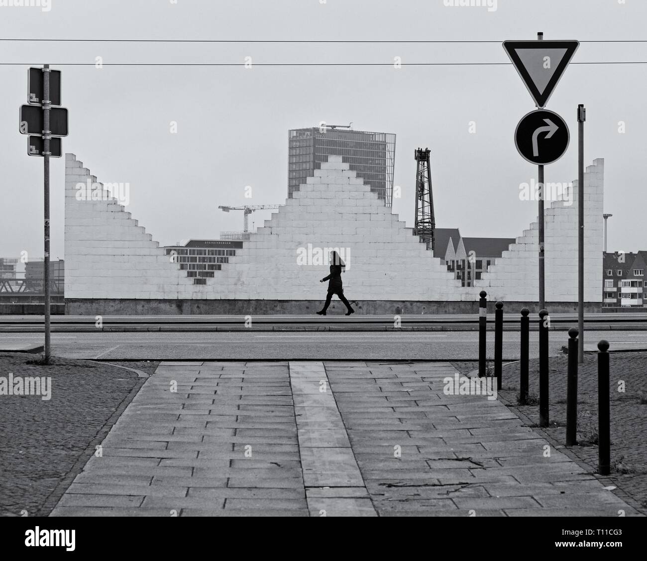 Bremen, Germania - Dicembre 31st, 2018 - Scene di strada con donna solitaria camminando su un marciapiede davanti a una grande scultura in bianco Foto Stock