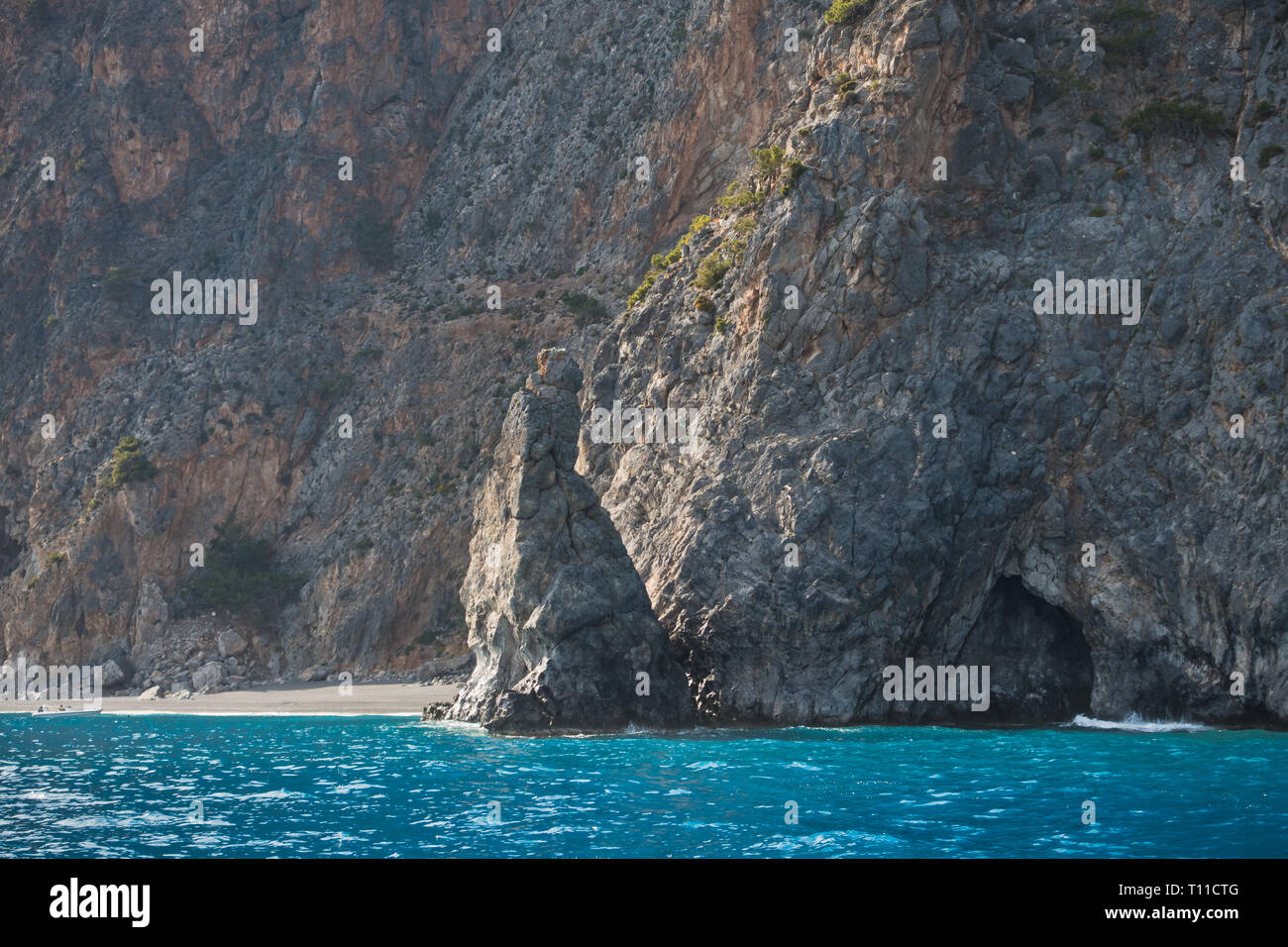 Scogliere con grotte circostanti spiaggia domata, vista dal traghetto ona strada tra Agia Roumeli e Sougia, a sud-ovest di Creta, Grecia Foto Stock
