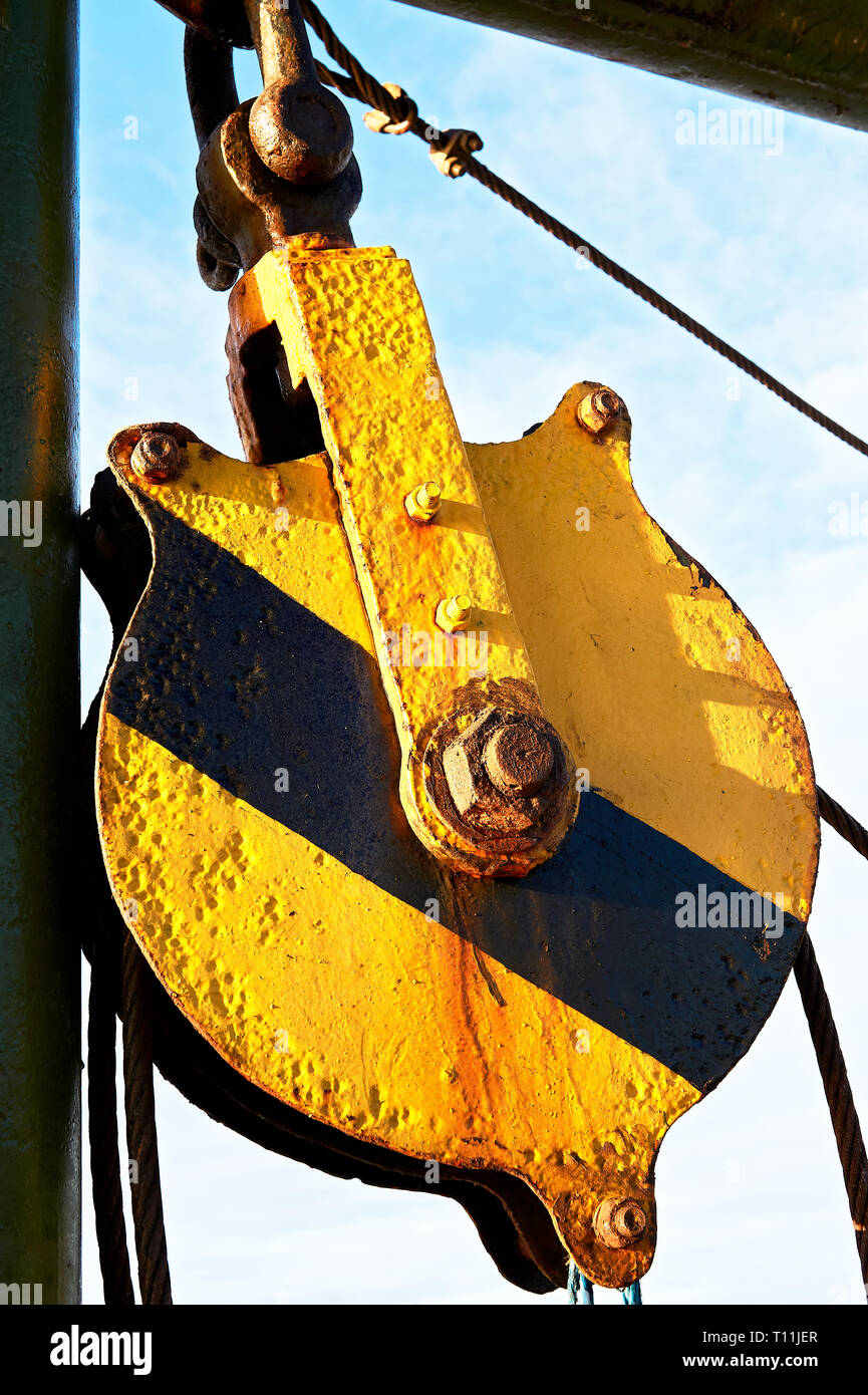 Close-up di un vecchie e arrugginite ruota della puleggia, dipinte in giallo e nero i colori di avvertimento, visto su un inter-isola nave nelle Filippine Foto Stock