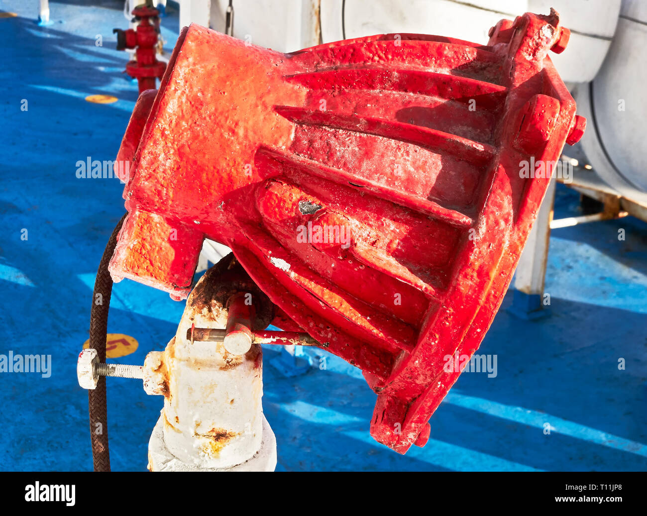 Close-up di un rosso ruggine verniciato a polvere di colore luce flood contro un piano di colore blu sul ponte di una nave in Asia Foto Stock