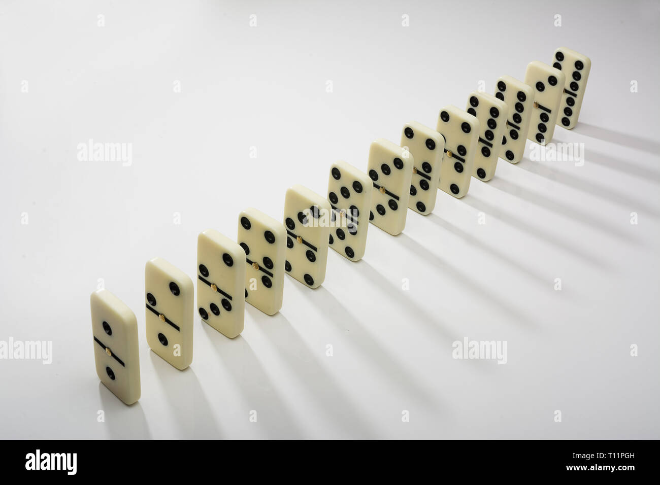 Domino piastrelle in fila su sfondo bianco Foto Stock