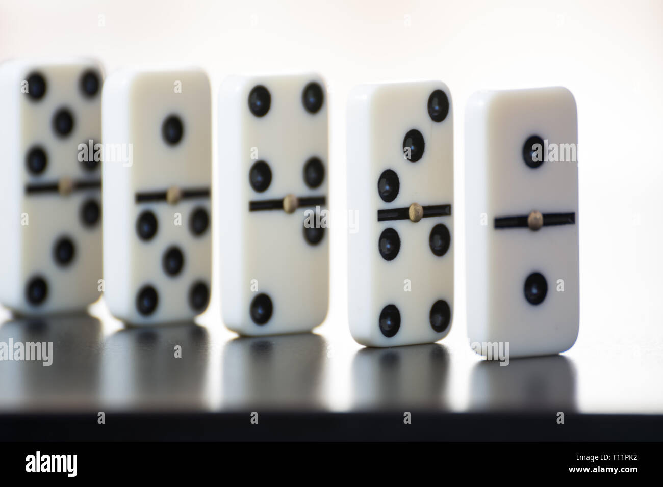 Domino piastrelle in fila su uno sfondo nero Foto Stock