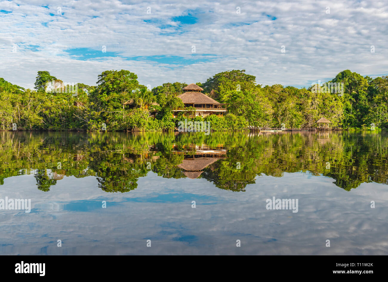 La riflessione di una foresta pluviale amazzonica lodge nella giungla di Yasuni National Park da una laguna, Ecuador. Foto Stock