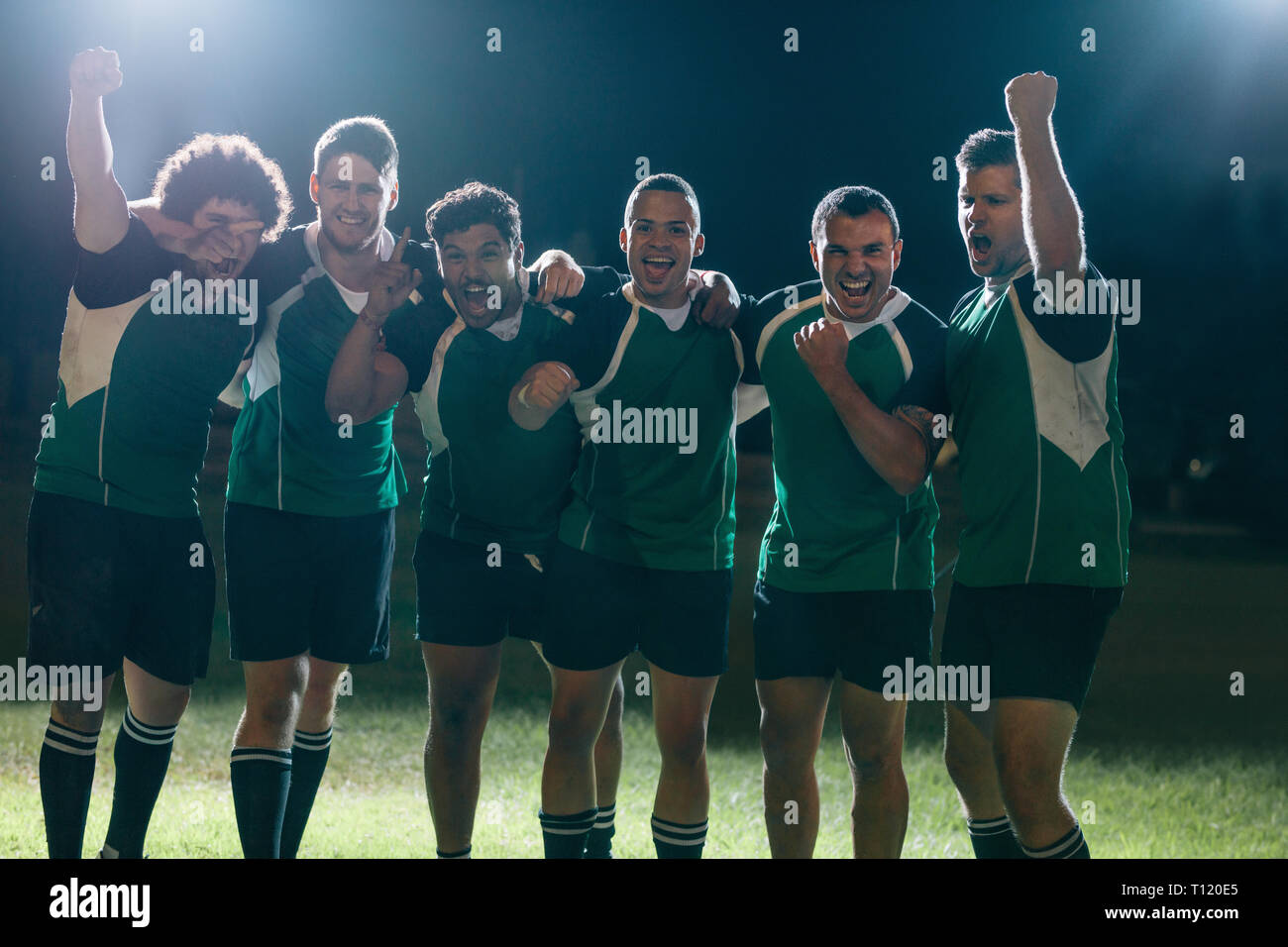 Professional giocatori di rugby celebra la vittoria su un'arena sportiva. Un gruppo di giocatori di rugby a urlare e punzone aria dopo aver vinto il gioco su sport fie Foto Stock