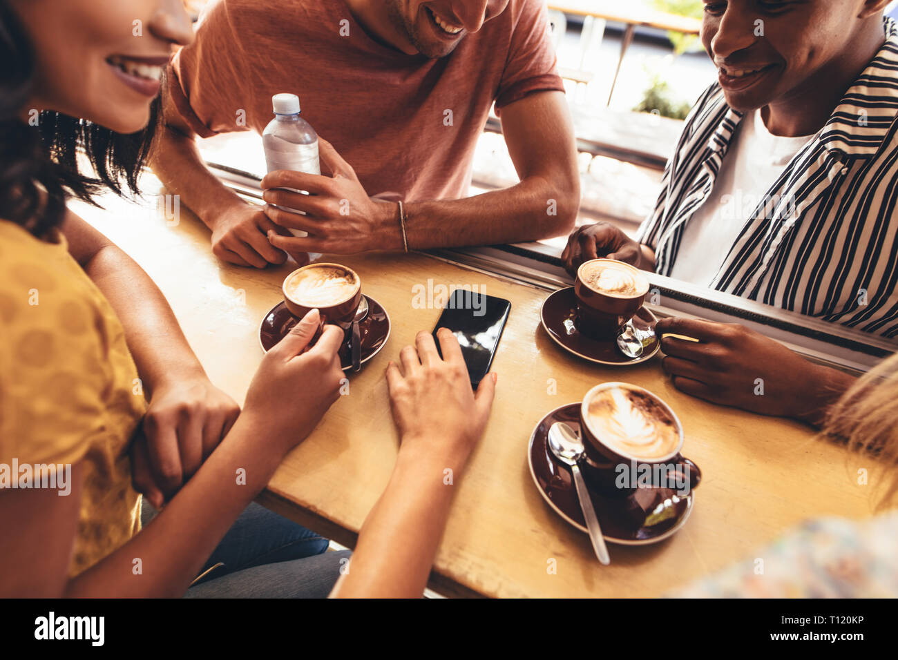 Gruppo di persone creative che si incontrano nel presso il cafe e discutere su nuovi contenuti per i social media. Giovani uomini e giovani donne sedute presso la caffetteria tabl Foto Stock