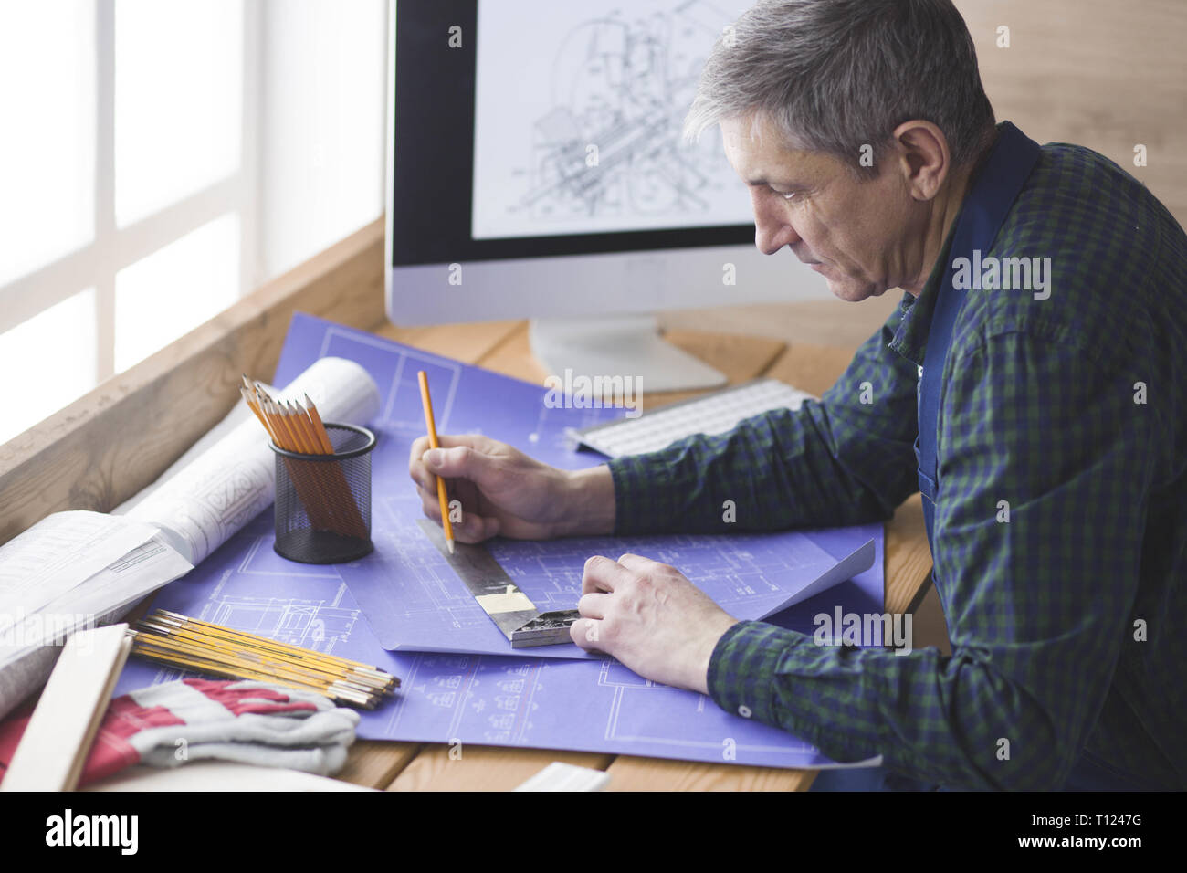 Ingegnere carpenter lavorando su laptop e schizzi di progetto Foto Stock