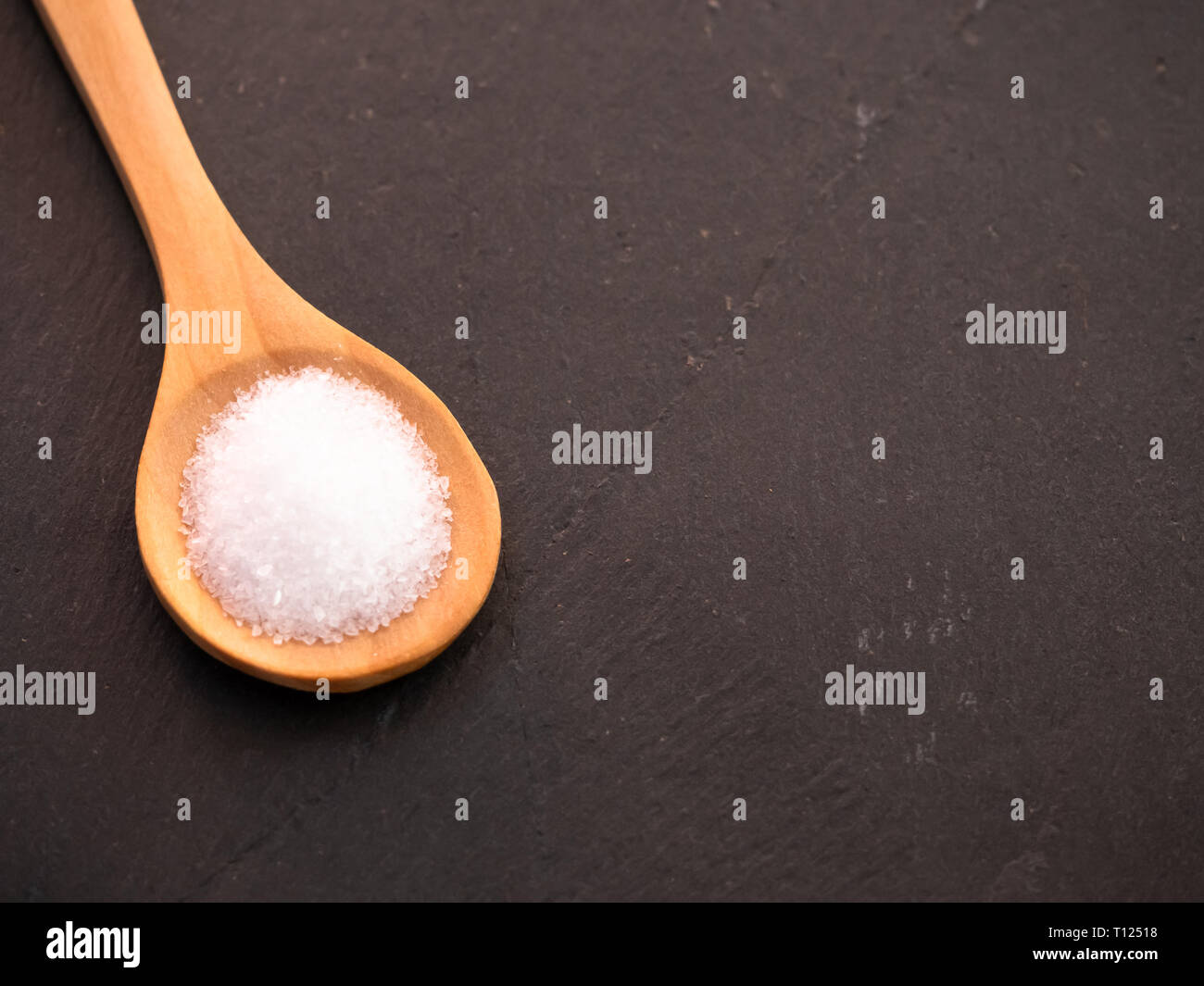 Il cucchiaio di legno con marine sale comune su una piastra di ardesia Foto Stock