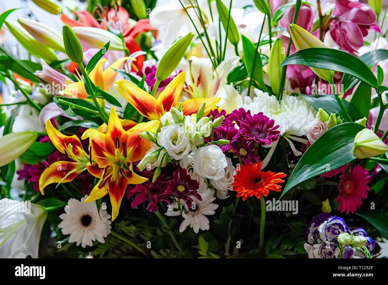 Grande e bel bouquet di crisantemi, orchidee e gerbere con un grande giglio giallo in un negozio di fiori. Foto Stock