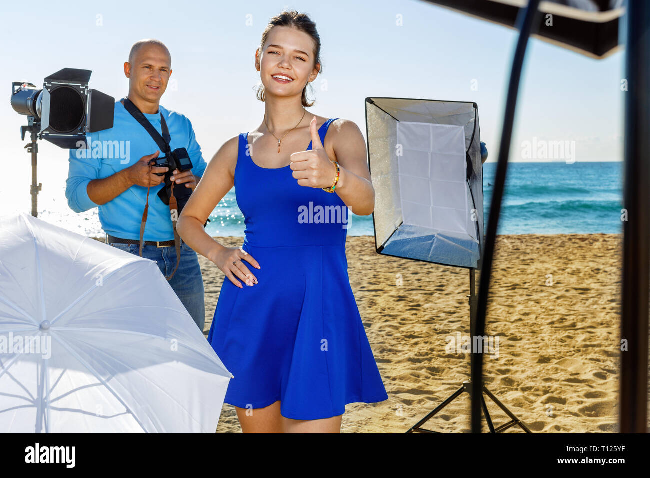 Giovani allegro sorriso positivo attraente modello femminile deliziati con foto professionali le riprese il mare con il fotografo maschio Foto Stock