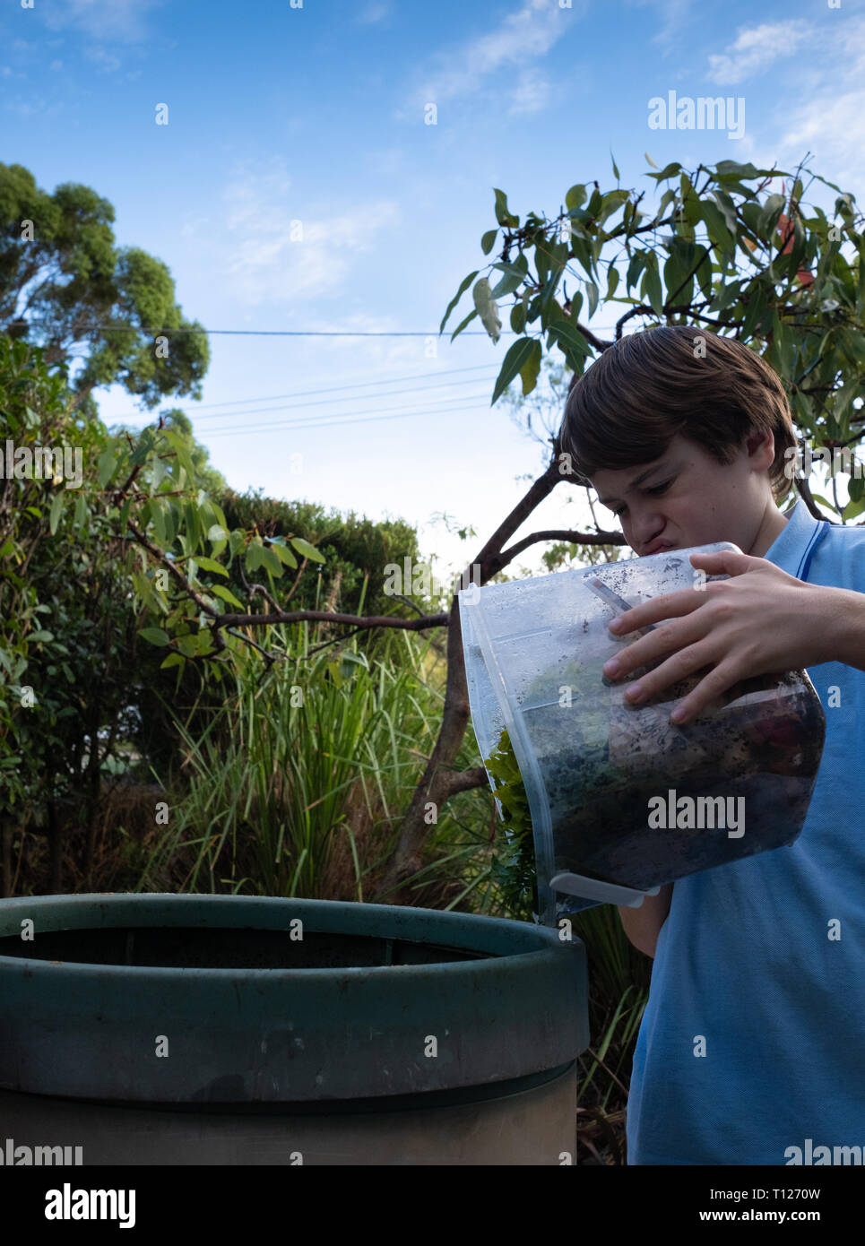 La scuola primaria di età bambino il ribaltamento di scarti di cibo in compost bin. Foto Stock
