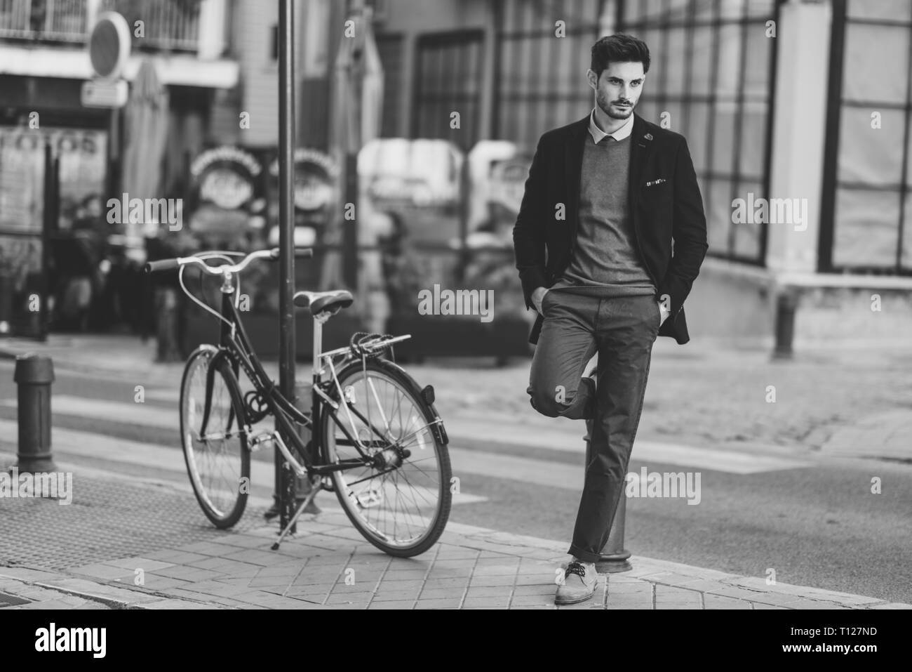 Uomo che indossa british elegante abito in strada vicino a una vecchia bicicletta Foto Stock