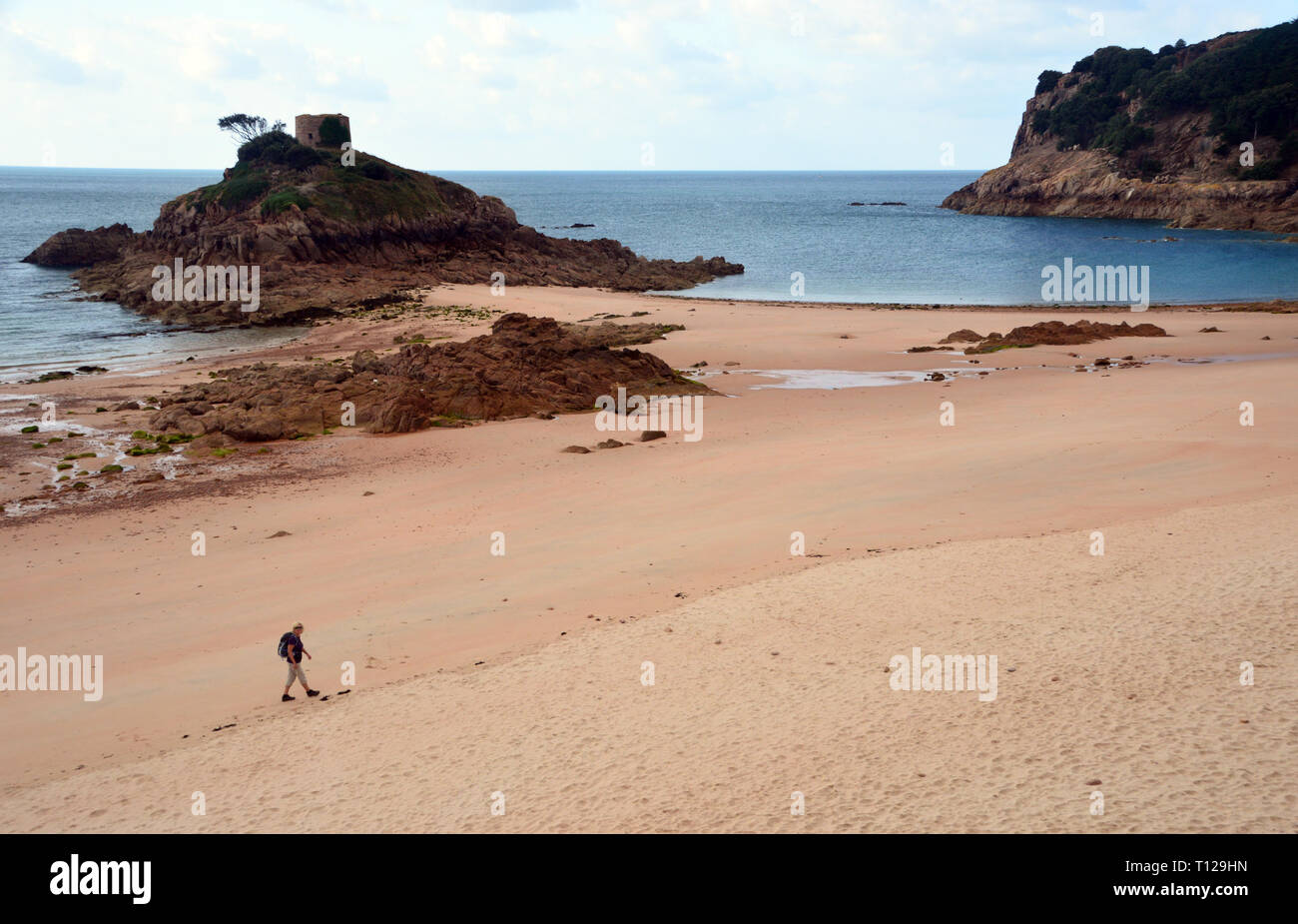 La donna gli escursionisti a piedi sulla spiaggia vicino Portelet Tower su un isola rocciosa nella baia di portlet, Saint Brélade parrocchia sull'isola di Jersey, nelle Isole del Canale. Foto Stock