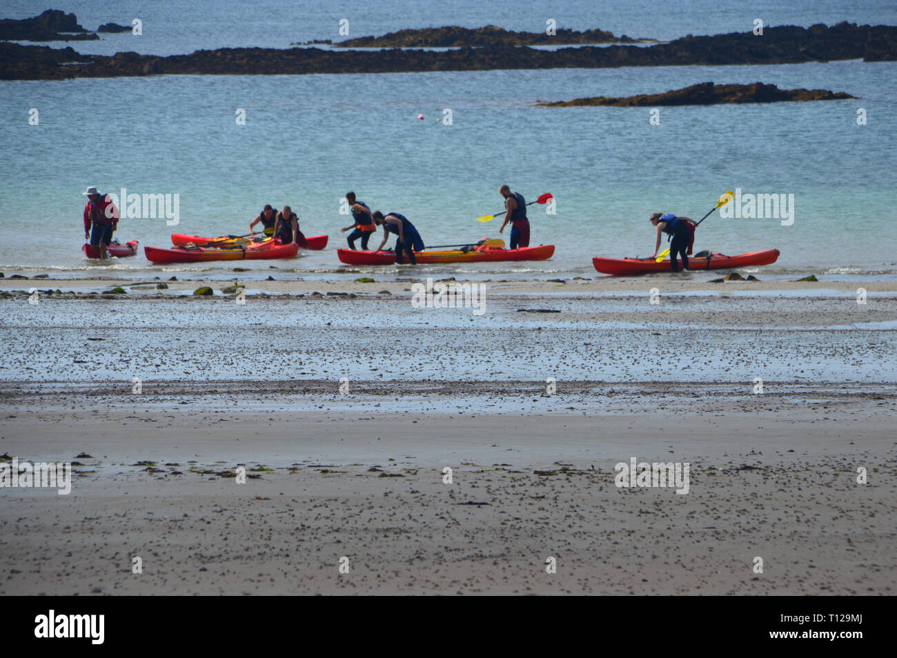 Canoisti sbarco cinque Orange canoe su St Brelade's Bay sull'isola di Jersey, nelle Isole del Canale, UK. Foto Stock